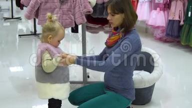 一个可爱的小女孩和她的母亲在一家<strong>精品</strong>店里家<strong>精品</strong>店。 妈妈和孩子在商店里挑选衣服